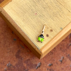 May include: A gold charm in the shape of a ladybug with black spots and green enamel.