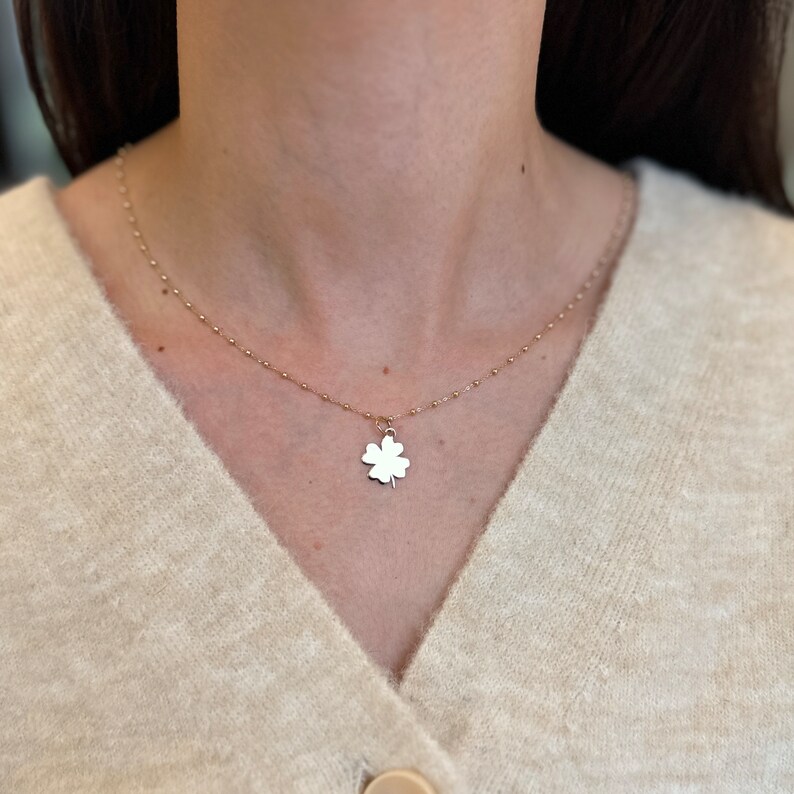 Puede incluir: Un collar de cadena dorada con un colgante de tr&eacute;bol de cuatro hojas.