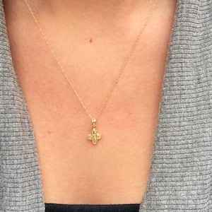 Op de afbeelding: Een gouden ketting met een klein, gedetailleerd kruisje als hanger.