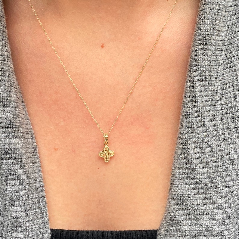 Op de afbeelding: Een gouden ketting met een klein, gedetailleerd kruisje als hanger.