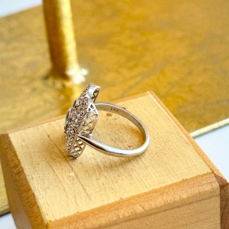 May include: A silver ring with a floral design and small diamonds. The ring is marked "14K" on the band.