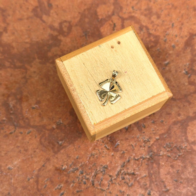May include: A gold four-leaf clover charm pendant in a wooden box.