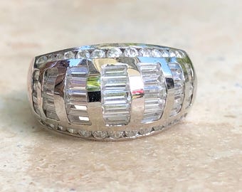 May include: A silver ring with a wide band set with baguette and round diamonds.