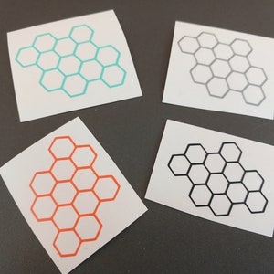 Può includere: Quattro carte bianche con disegni a nido d'ape. I favi sono in turchese, nero, arancione e grigio.