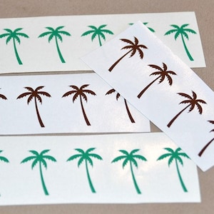 Op de afbeelding: Vier vellen wit papier met bruine en groene palmboom stickers. De stickers zijn gerangschikt in rijen en kolommen.