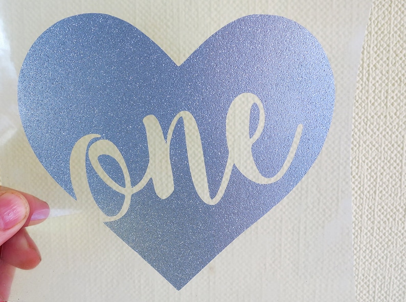 May include: A blue glitter heart with the word "one" in white script inside.