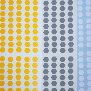 Puede incluir: Tres hojas de papel blanco con filas de pegatinas hexagonales. Las pegatinas son amarillas, grises y blancas.