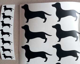 May include: A sheet of black dachshund silhouette stickers. The stickers are arranged in a row, with the dachshunds facing to the right. There are 10 stickers in total.