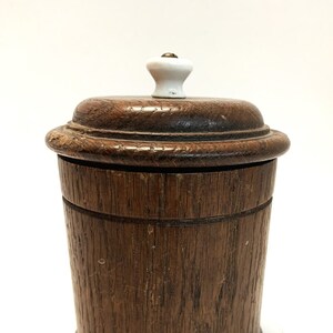 Peut inclure: Un pot en bois avec un couvercle et un bouton blanc. Le pot est brun et a un grain de bois naturel. Le couvercle est également en bois et a une surface lisse.