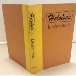 Peut inclure: Un livre relié de couleur jaune et marron intitulé "Heloise's kitchen hints".