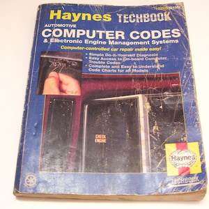 May include: A blue Haynes Techbook titled "Computer Codes & Electronic Engine Management Systems". The cover features a photo of a car's dashboard with a "Check Engine" light and a hand holding a wire.