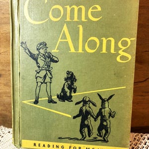 May include: A vintage children's book titled "Come Along" with yellow lettering on a green cover. The cover features illustrations of a conductor, a dog, and two figures with rabbit ears. The text "Reading for Meaning" is at the bottom.