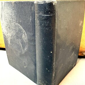 May include: A well-worn, dark blue hardcover book, titled "The Oxford Dictionary" on the spine. The book shows signs of age with wear and discoloration. The cover has a faded design. A classic reference work.