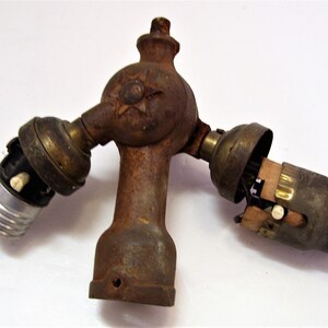 May include: A vintage, three-way, cast iron light fitting with brass sockets and a star-shaped design. The fitting is rusty and shows signs of age.