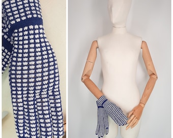 May include: A pair of blue and white knit gloves with a geometric pattern. The gloves are shown on a mannequin hand.