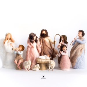 Könnte beinhalten: Eine Filz-Krippe mit einem weißen Engel, einem Hirten, einer Frau, einem Mann, einem Baby in einer Krippe und zwei Schafen. Die Figuren spielen alle Musikinstrumente.
