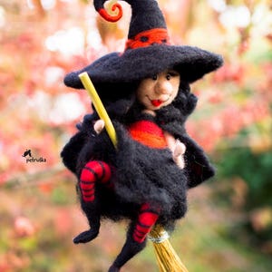May include: A black felt witch doll with a red and black hat and a red and black striped dress, riding a brown broom.