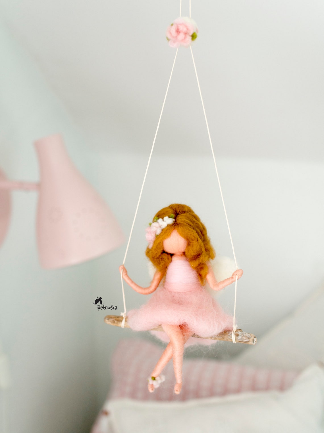 A needle felt fairy swinging on a swing.