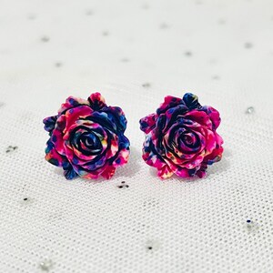 May include: A pair of rose-shaped stud earrings with a pink, blue, and yellow floral pattern.