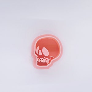 Op de afbeelding: Een roze plastic koekjesvormpje in de vorm van een schedel.