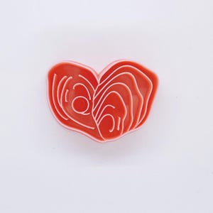 May include: A red heart-shaped pin with a white outline depicting a salmon fillet.