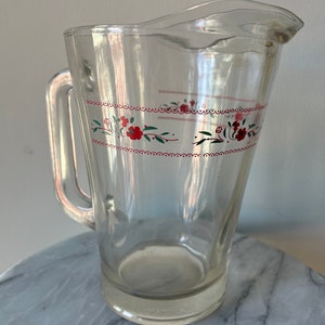 Vintage heavy glass pitcher with small red floral design.