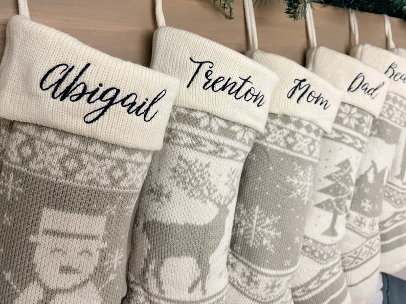 May include: Set of six gray and white knit stockings with personalized names: Abigail, Trenton, Mom, Dad, Ben, and Grandma. The stockings feature a snowflake and reindeer design.