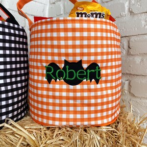 May include: Orange and white gingham fabric trick-or-treat bucket with a black bat and the name "Robert" embroidered on the front.