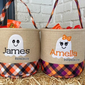 May include: Two burlap trick-or-treat bags with ghost designs. One bag is orange and black plaid with the name Amelia and the text "Orange&Swizzle". The other bag is black and white plaid with the name James and the text "Black&Swizzle".