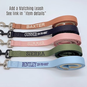 May include: Five personalized dog leashes in different colors, including brown, black, pink, green, and blue. Each leash has a metal clip and is embroidered with a dog's name and phone number.
