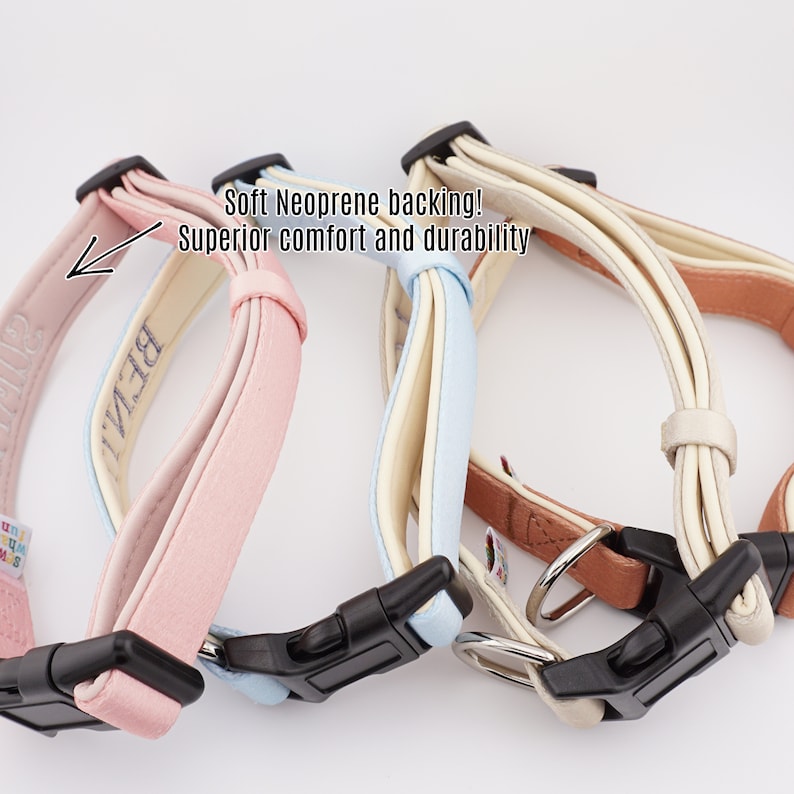 May include: Three dog collars in pink, light blue, and cream with black buckles. The collars have a soft neoprene backing for comfort and durability. The pink collar has the word "BELLA" embroidered on it.