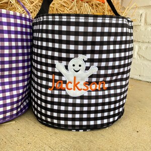 May include: Black and white gingham trick-or-treat bucket with a white ghost and the name "Jackson" embroidered in orange.