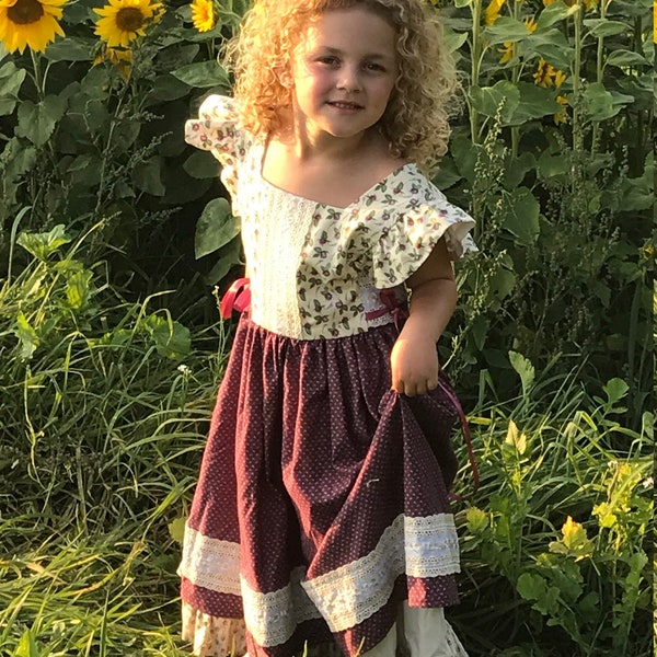 Heirloom with a vintage look multi layered girl' dress. This has ruffles, lace, and pinafore design by Violet Field Threads