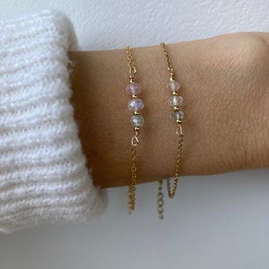 May include: Two delicate gold chain bracelets with small pink and clear gemstone beads.