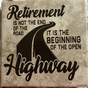 May include: Square tile with the text "Retirement is not the end of the road, it is the beginning of the open highway" in black script. The design includes a stylized road graphic. The background is a mottled beige.