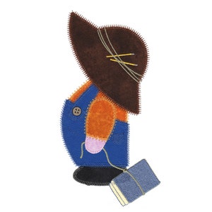 May include: A felt appliqué of a person wearing overalls, a brown hat, and holding a blue book. The person is orange, blue, and pink.