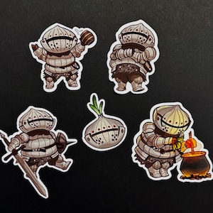 Op de afbeelding: Een set van vijf stickers met stripfiguren in ronde, gesegmenteerde harnassen die op uien lijken. Eén figuur houdt een vat vast, één staat met gekruiste armen, één houdt een zwaard en schild vast, één is een uienhelm en één roert in een pot.