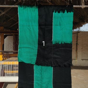 Peut inclure: Textile rectangulaire avec un motif patchwork. Le textile présente des panneaux verticaux alternés noirs et verts. Les panneaux verts ont une frange en bas. Le chiffre "1" est visible sur le textile.