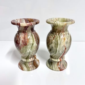 May include: Two green and red marble vases with a swirling pattern. The vases are about 6 inches tall and have a round base.