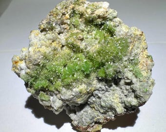 May include: A green and white mineral specimen with a rough, textured surface. The specimen is covered in small, green crystals.