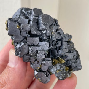 May include: A cluster of gray galena crystals with a metallic sheen. The crystals are intergrown and have a cubic shape. Some of the crystals have a golden pyrite coating.