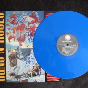 May include: A blue vinyl record with the text "Guns N' Roses" and "Appetite for Destruction" on the cover. The record is signed by the band members.