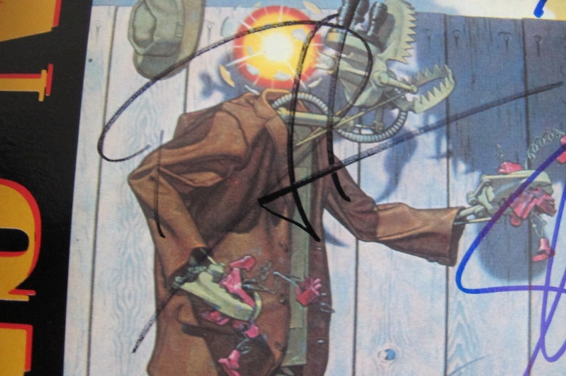 May include: A vintage record album cover featuring a robot-like figure wearing a brown jacket and a hat. The figure is holding a tool in its hand. The album cover is signed by four different people in black and blue ink.
