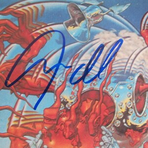 May include: A blue and white album cover with a signature in blue ink that says "Gall". The cover features a red and silver robot with multiple arms.