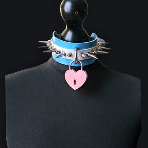 May include: A blue and white leather choker with silver spikes and a pink heart-shaped padlock.
