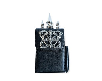 May include: A black leather cigarette case with a silver pentagram design and three silver spikes on top.