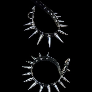 May include: Two black leather collars with silver spikes. The collars are shown from the top, with the spikes pointing outwards.