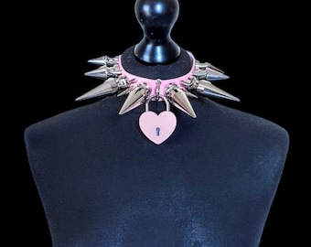 May include: Pink faux leather choker with silver spikes and a heart-shaped padlock.
