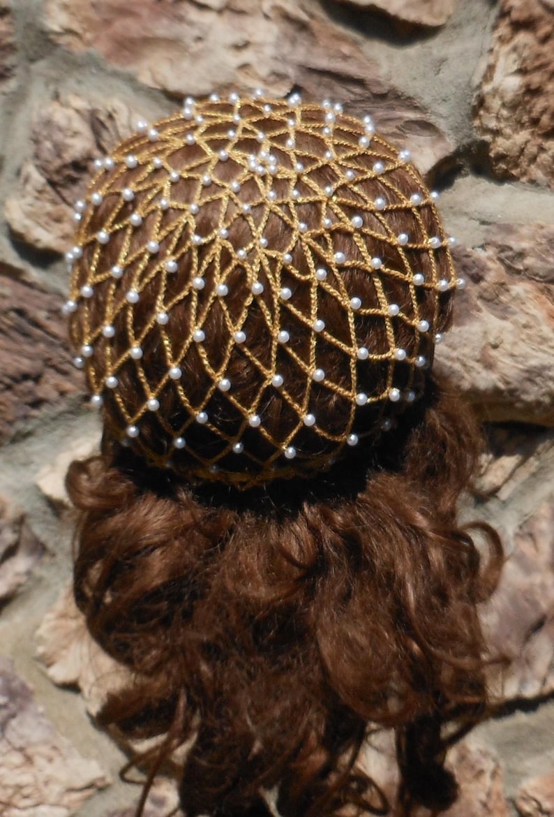 Op de afbeelding: Een gouden gaas haarnet met witte parel kralen. Het net wordt gedragen over bruin haar.