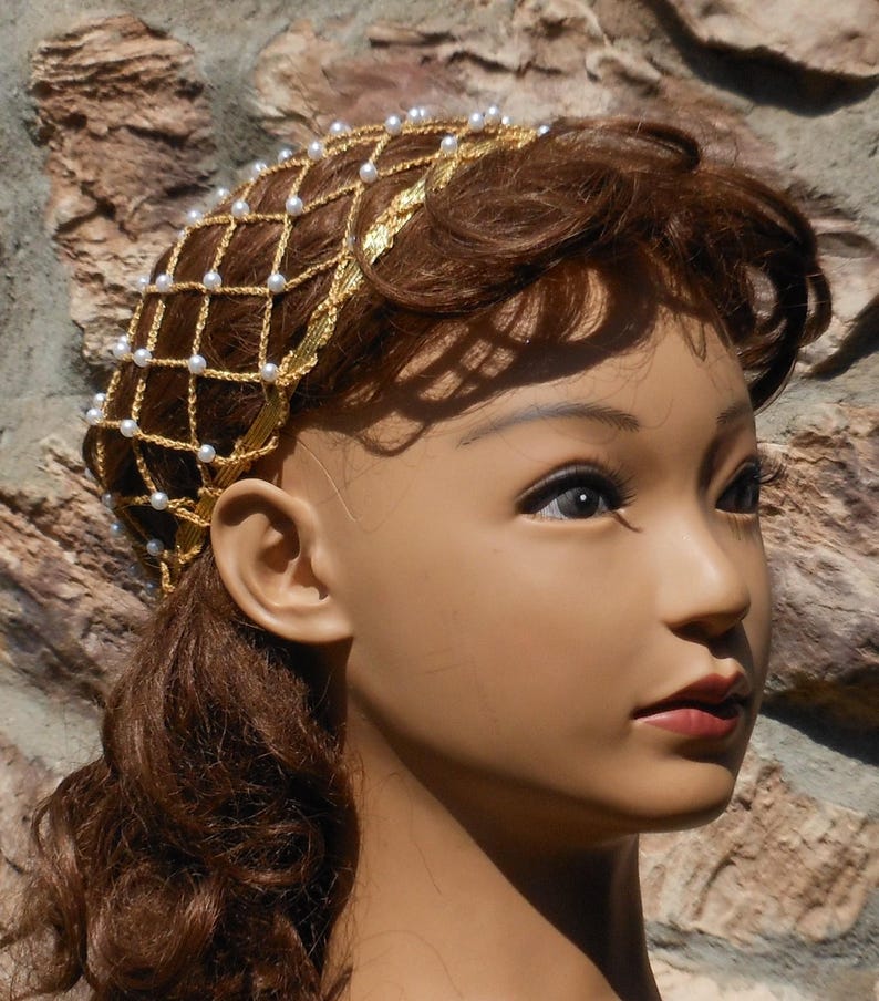 Op de afbeelding: Een gouden draad haarnet met witte parels, gedragen door een mannequin met bruin haar.